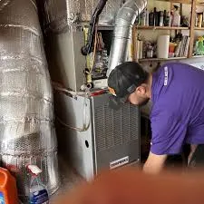 A technician from Mason Plumbing, Inc. works on a furnace system in San Anselmo, surrounded by ductwork and tools.